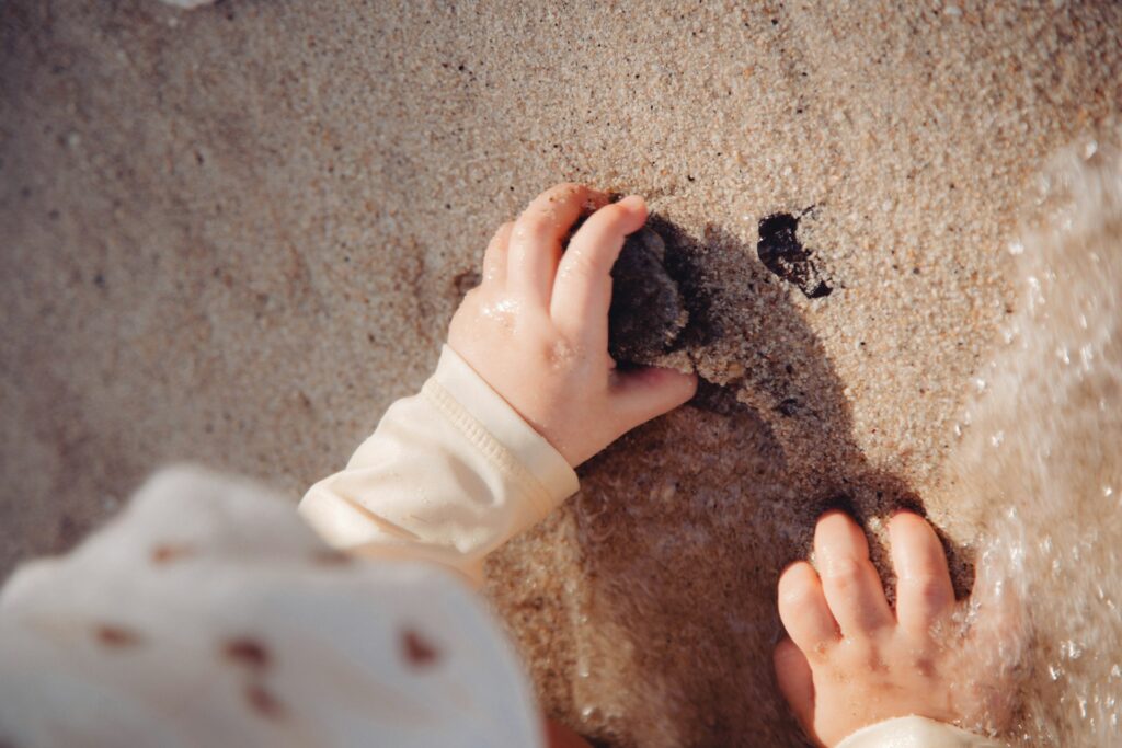 criança a explorar grãos de areia para desenvolver motricidade fina